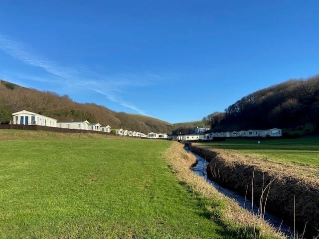 view of open field in the bottom of a valley with caravans on either side